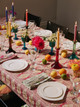 Atelier Véronique Mikado in hot pink used as a tablecloth, styled with foliage napkins, colourful glass candles, and a vibrant tablescape by Virginia White. Photography by Christopher Horwood.